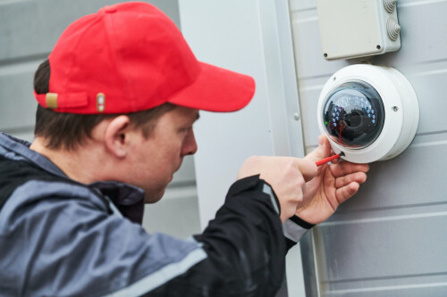 video surveillance system service. Technician installing camera indoors